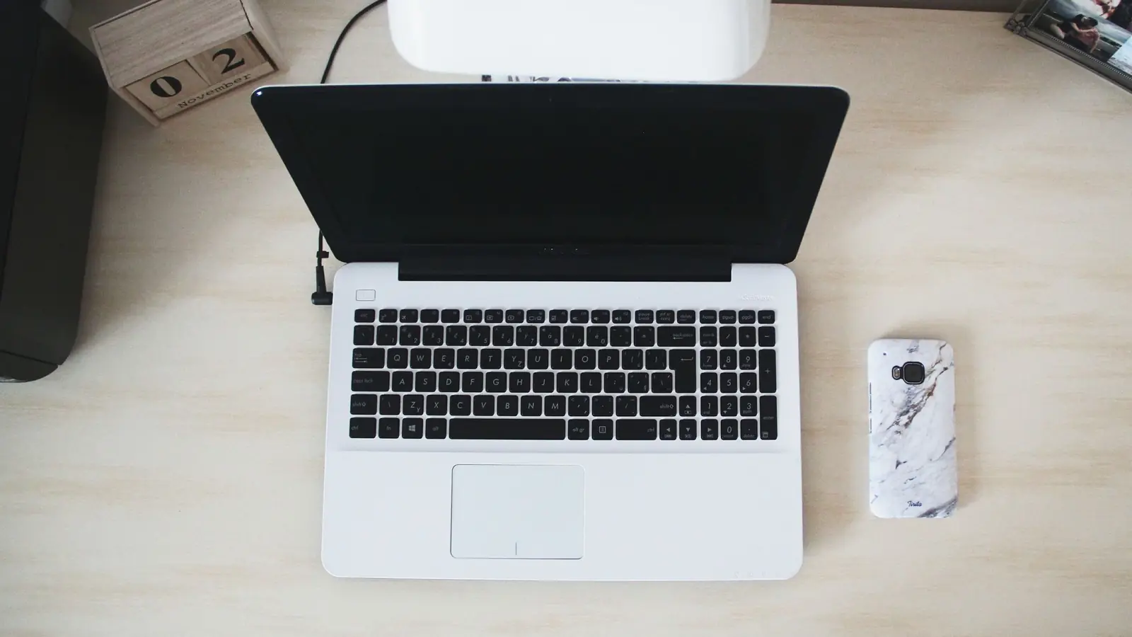 Laptop și telefon așezate pe un birou luminos, văzute de sus